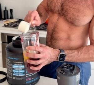Scooping protein powder into a blender to make high-protein muffins