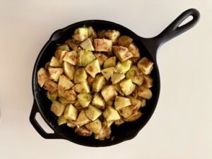 Granny Smith apple filling packed into a 10-inch cast iron skillet, coated in cinnamon and dark brown sugar.