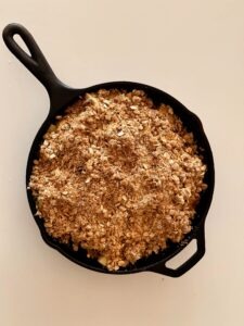 Overhead photo of unbaked apple crisp in a 10-inch cast iron skillet, filled with Granny Smith apples and a dark brown sugar oat crumble.