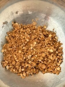 Dark brown sugar oat crumble mixture in a bowl, ready to be added on top of the apple filling.