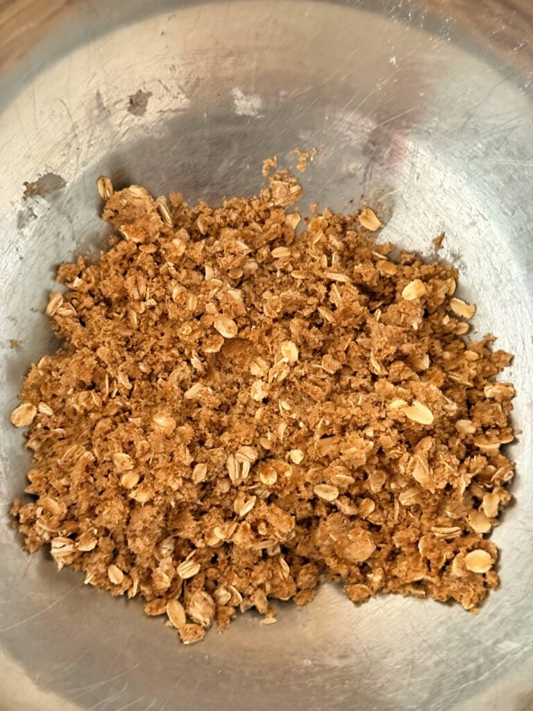 Dark brown sugar oat crumble mixture in a bowl, ready to be added on top of the apple filling.