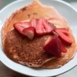 Fluffy golden protein pancakes stacked high with a drizzle of sugar-free syrup and a pat of melted butter.
