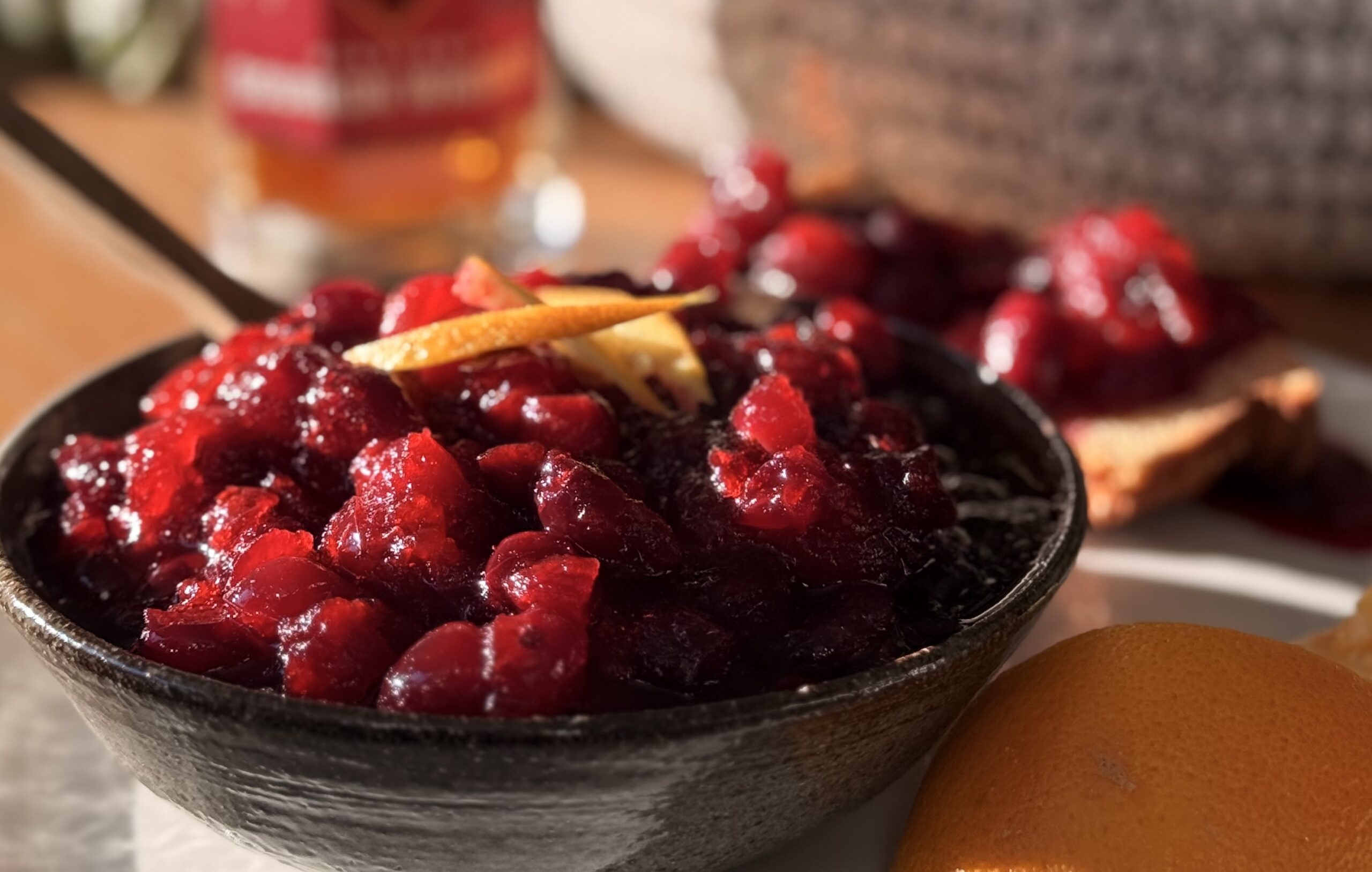 Bourbon cranberry sauce served in a small bowl with lemon peel on top
