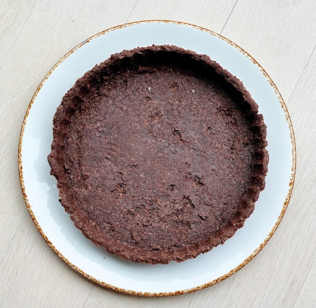 Finished low-carb chocolate tart crust on a white plate.