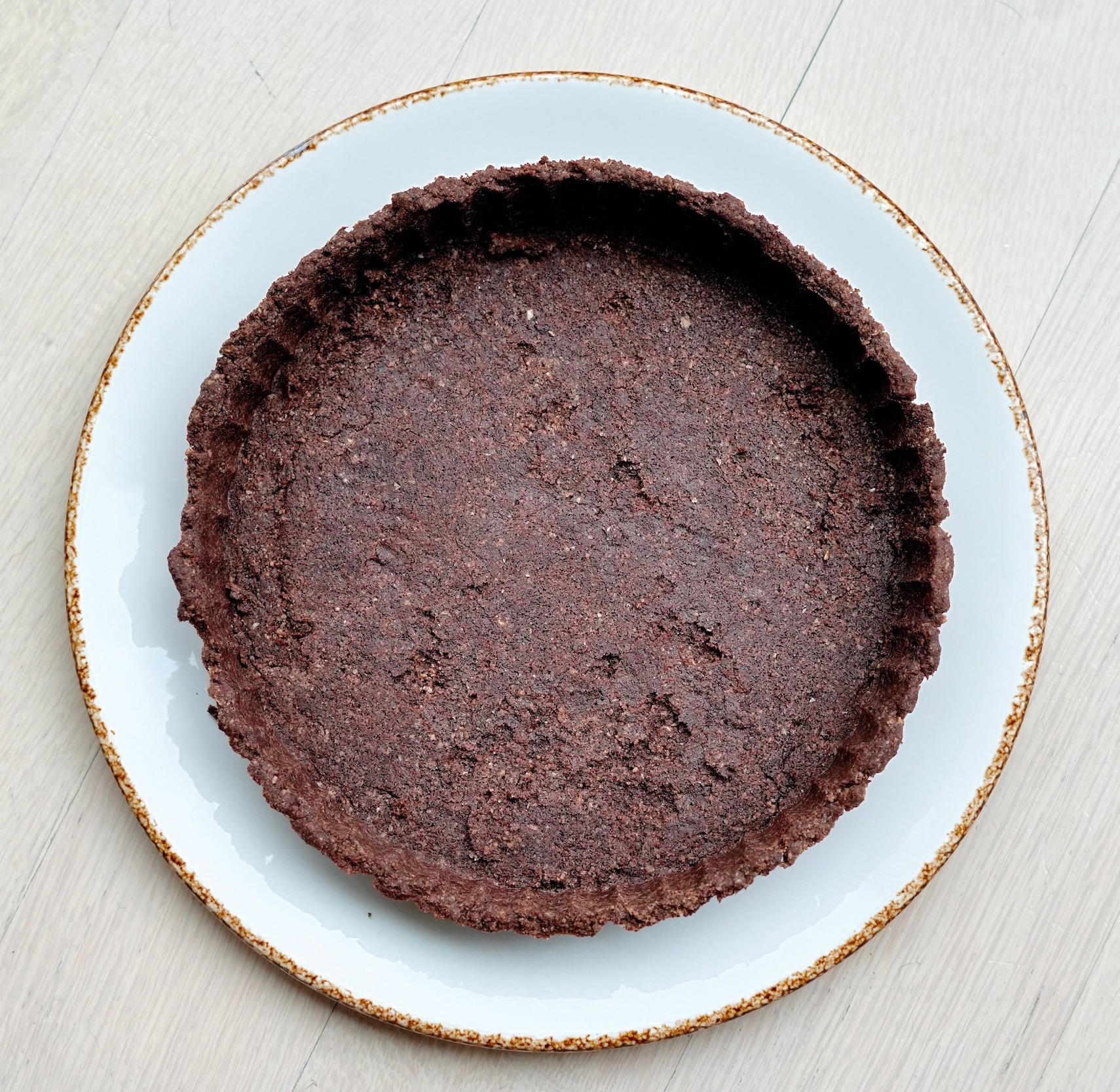 Finished low-carb chocolate tart crust on a white plate.