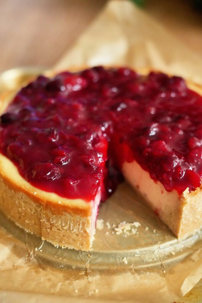 Close-up of cheesecake showing thick guava cranberry topping and graham crust.