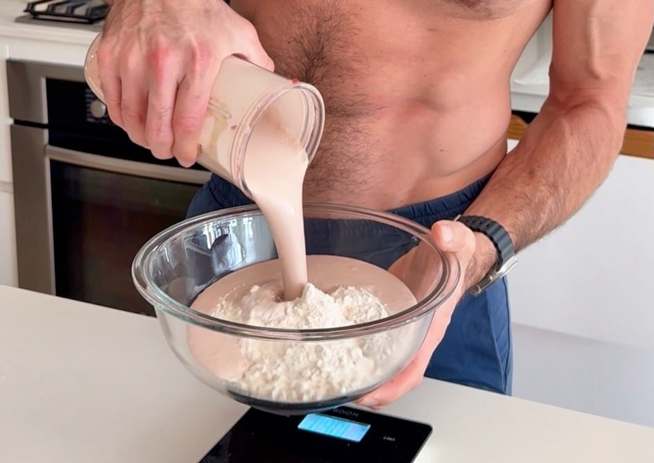 Protein shake poured into a bowl of dry ingredients for muffin batter
