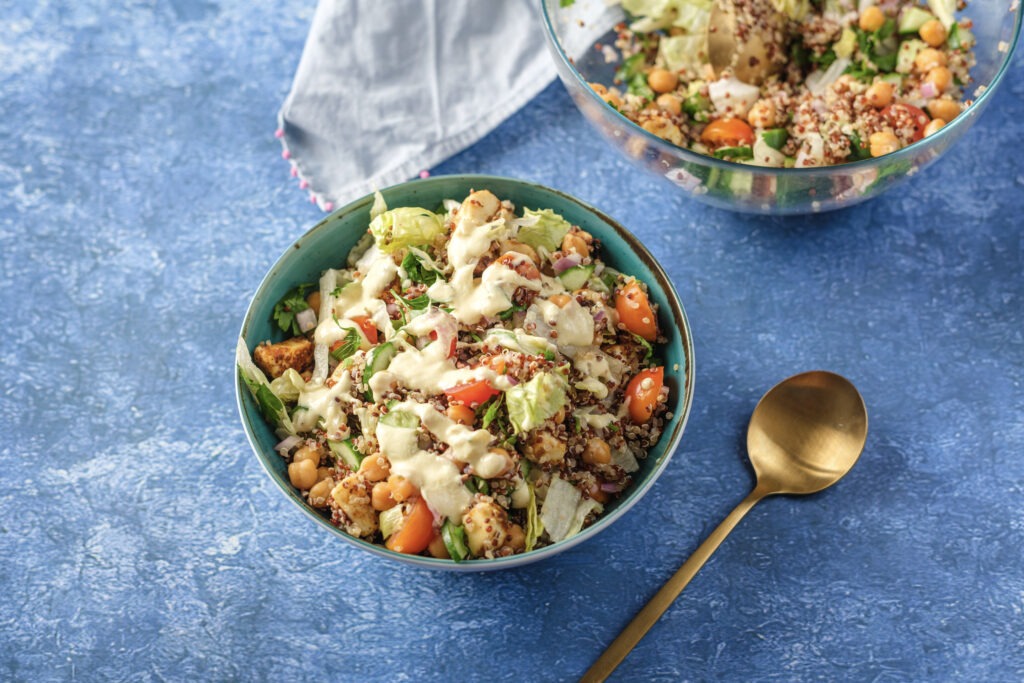 Close-up of a perfectly plated salad, highlighting the texture of the quinoa, diced vegetables, and the golden-brown crispy tofu pieces.