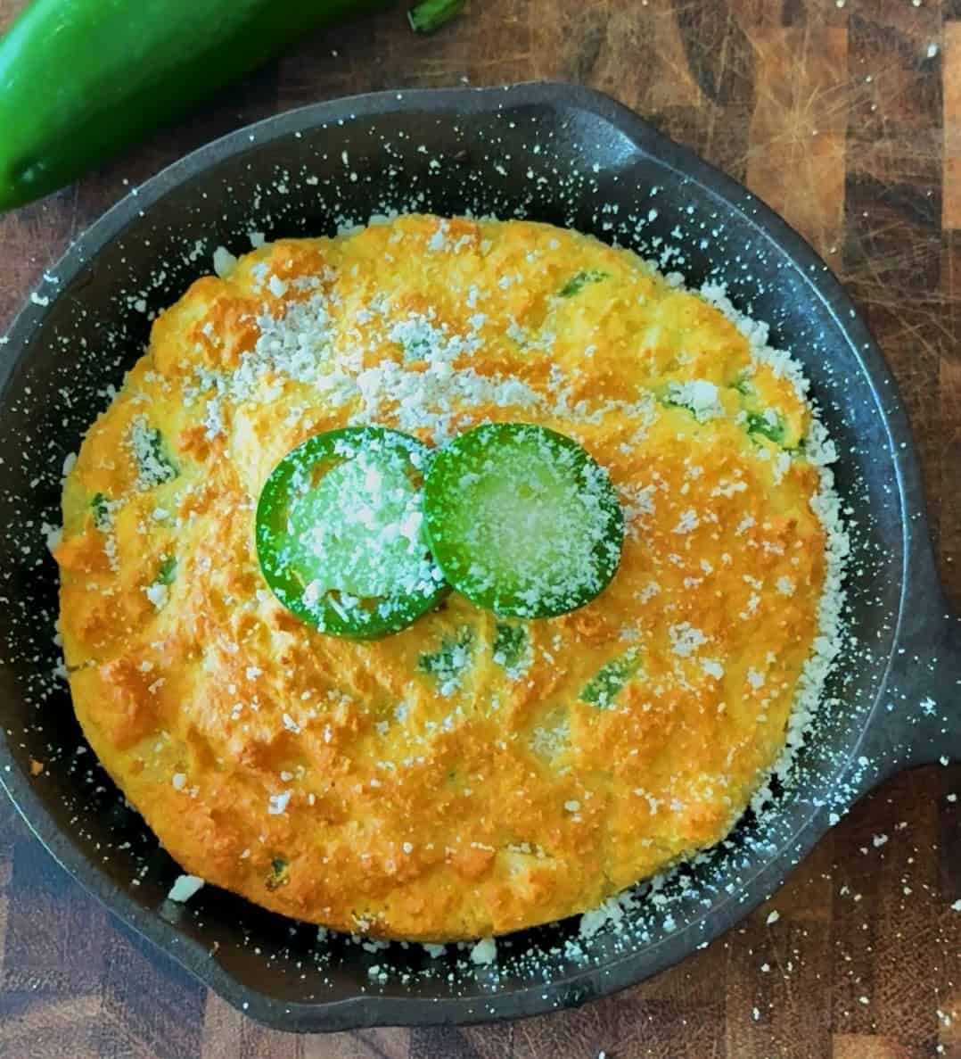 Baked cornbread in a cast iron skillet with a golden, slightly domed top.