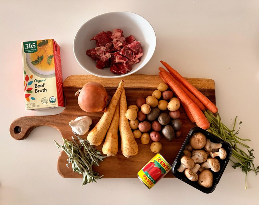 Ingredients prepped for beef and lamb stew on a cutting board with bowls and seasonings