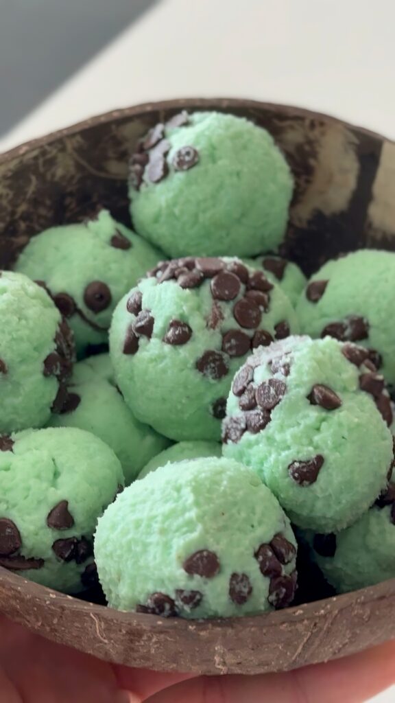 Close-up of thick, cohesive high-protein mint chocolate chip cookie dough with chocolate chunks on a spoon.