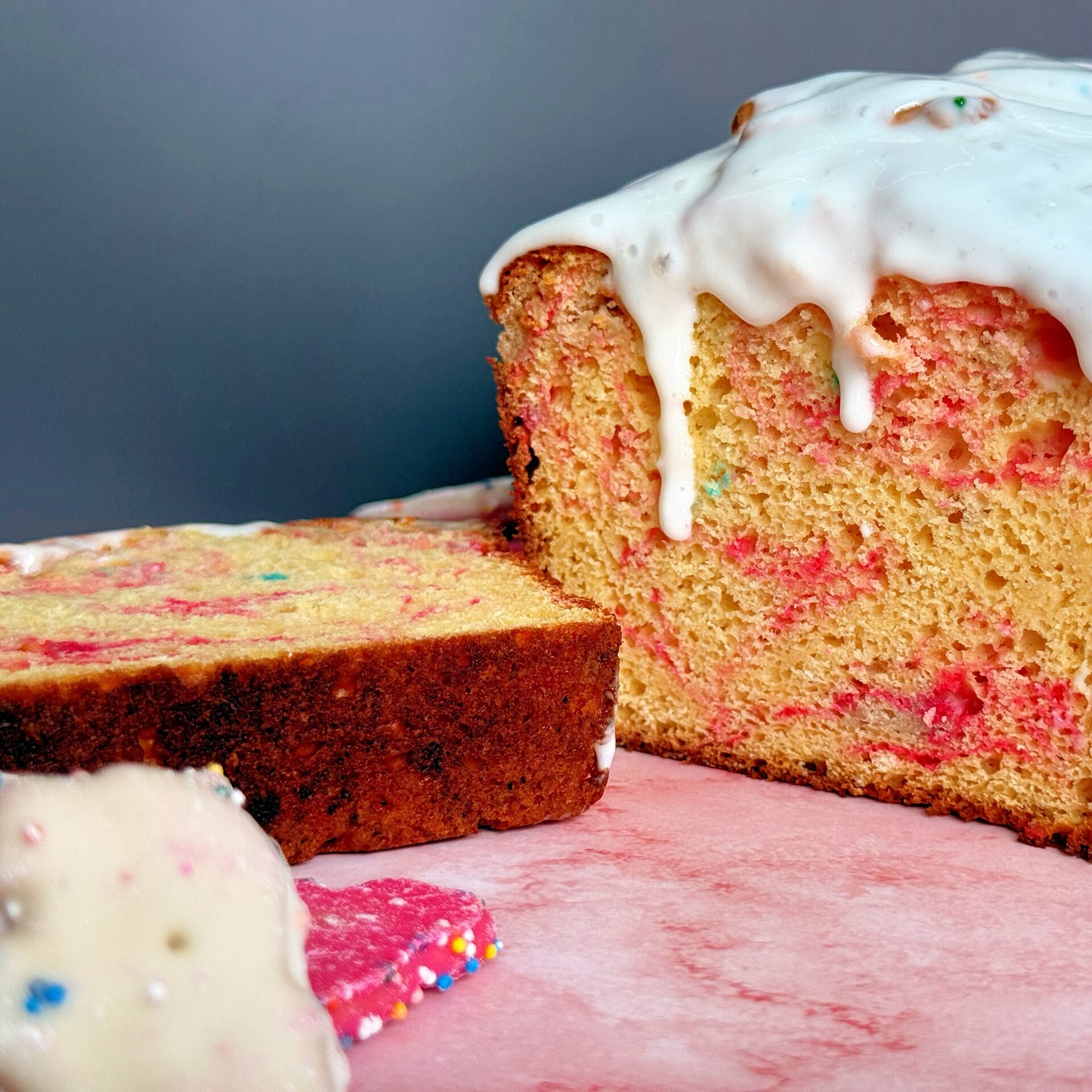 A bowl of pink and white iced animal crackers, crushed into fine pieces for folding into the high-protein loaf cake batter.