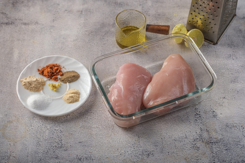 All ingredients for the high-protein grilled chicken Caesar salad laid out on a clean counter.