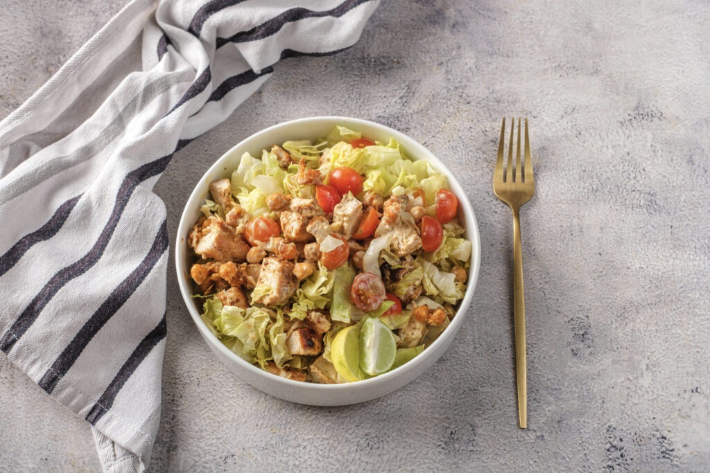 Tilted, appetizing view of the final Caesar salad showing the dressing drizzle and crispy chickpeas.
