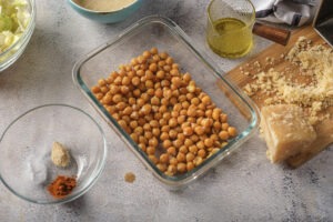 Dried cooked chickpeas and grated Parmesan cheese waiting in a glass dish before being baked for the salad.
