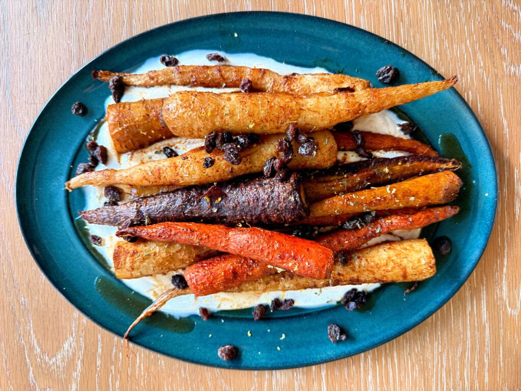 Jacob eating a harissa and maple glazed carrot over spicy yogurt sauce