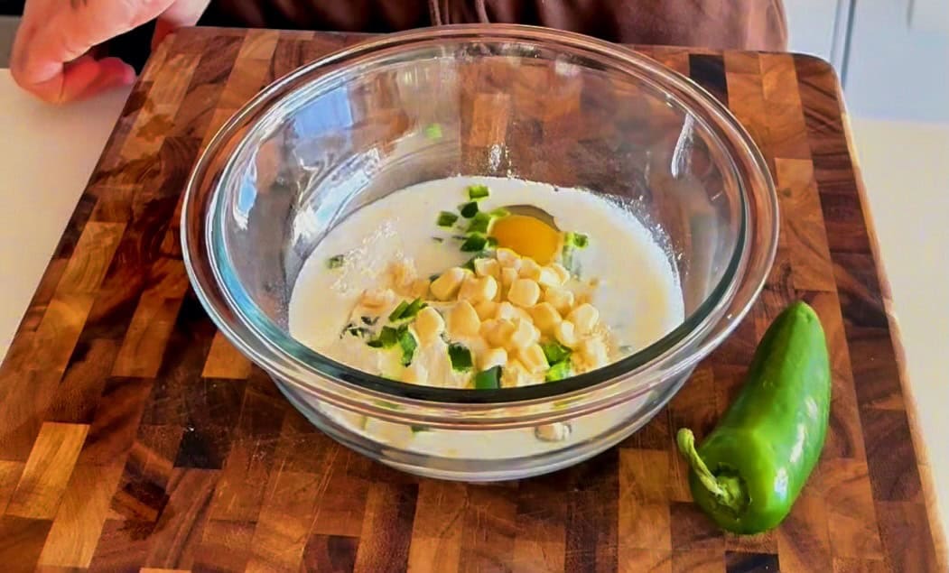 Single-serve cornbread protein batter with jalapeños being mixed in a glass bowl"