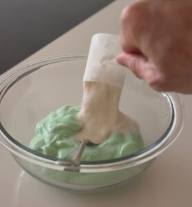 Scoop of PEScience Vanilla Select Protein Powder being added to the dough mixture.