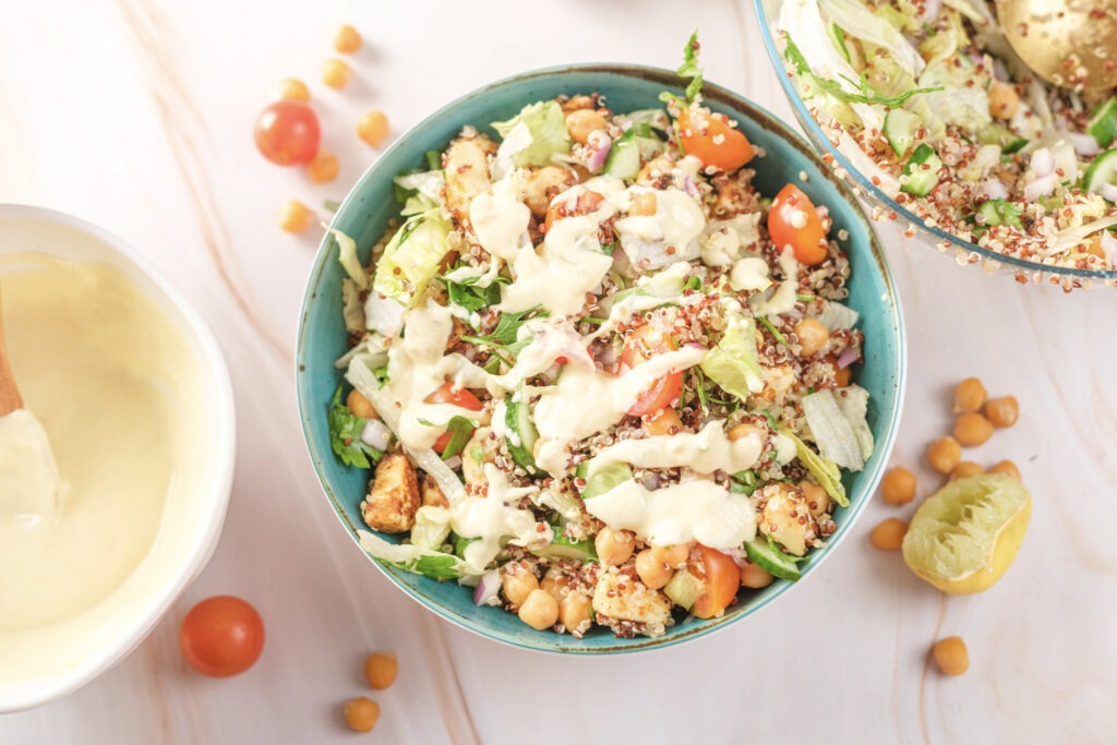 A side-angle view of the vegan salad in a bowl on a wooden surface, showing its height and layering of ingredients.