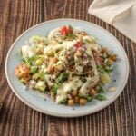 A vibrant, high-protein vegan quinoa salad topped with creamy lemon-tahini dressing, crispy baked tofu croutons, and chopped parsley.