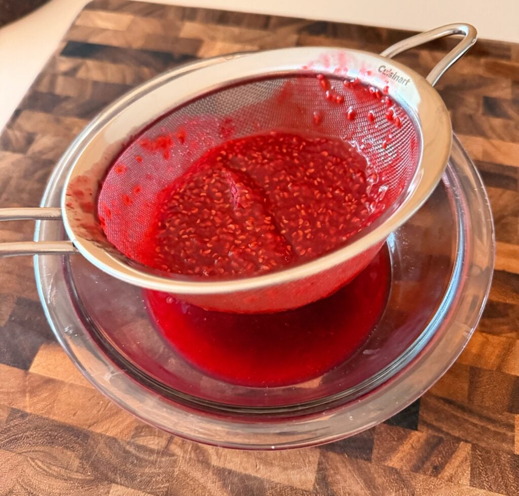 Homemade raspberry sauce being strained for torta caprese