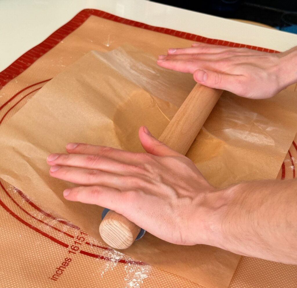Rolling vintage sour cream cookie dough between parchment paper