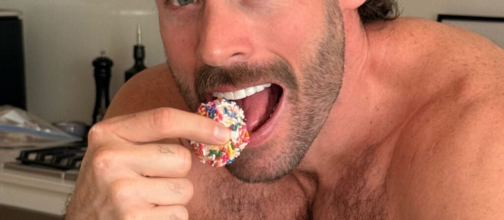 Man taking a bite of a sprinkle-covered cake pop