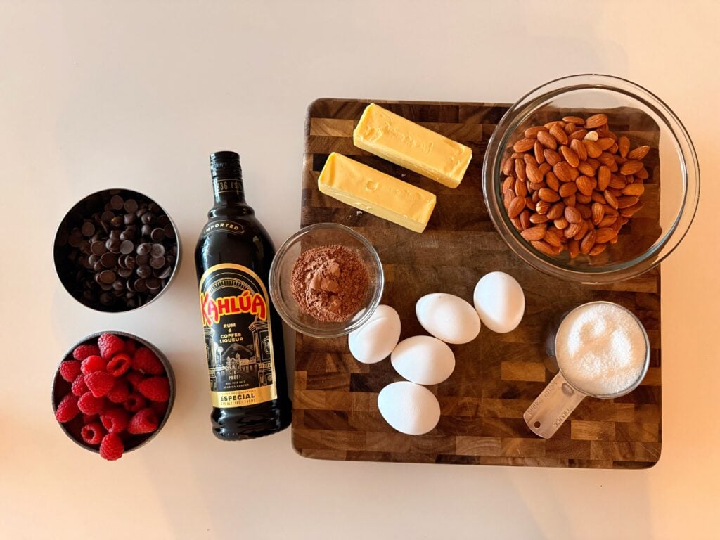 Ingredients for torta caprese including chocolate, eggs, butter, almonds, and raspberries