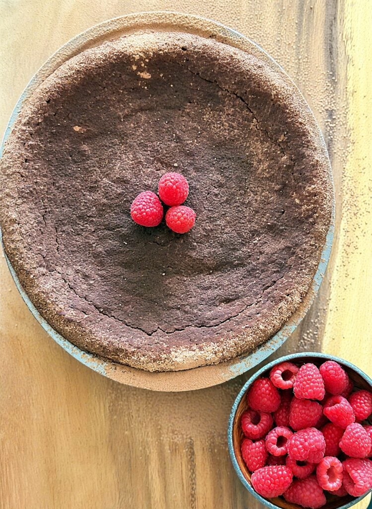 Torta caprese with bowl of fresh raspberries on the side
