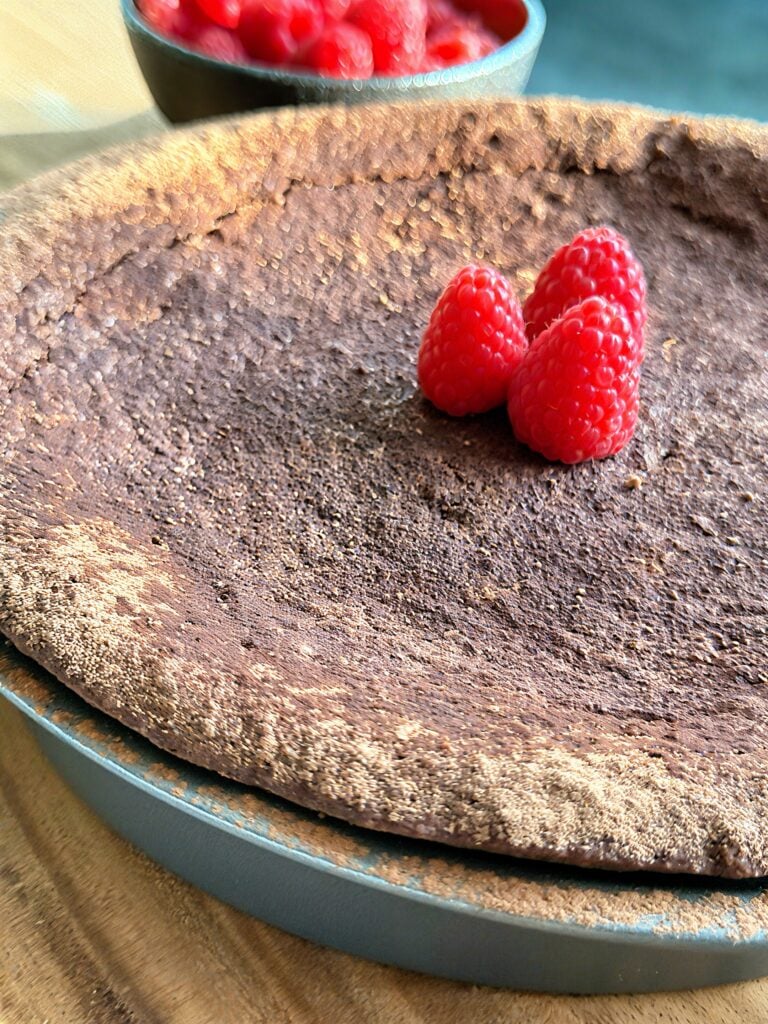 Torta caprese topped with fresh raspberries and cocoa-dusted surface