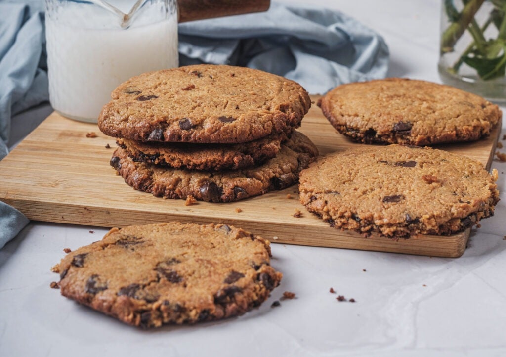 Vegan chocolate chip cookies laid out on a wooden cutting board
