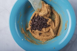 Scooping vegan chocolate chip cookie dough onto a baking sheet