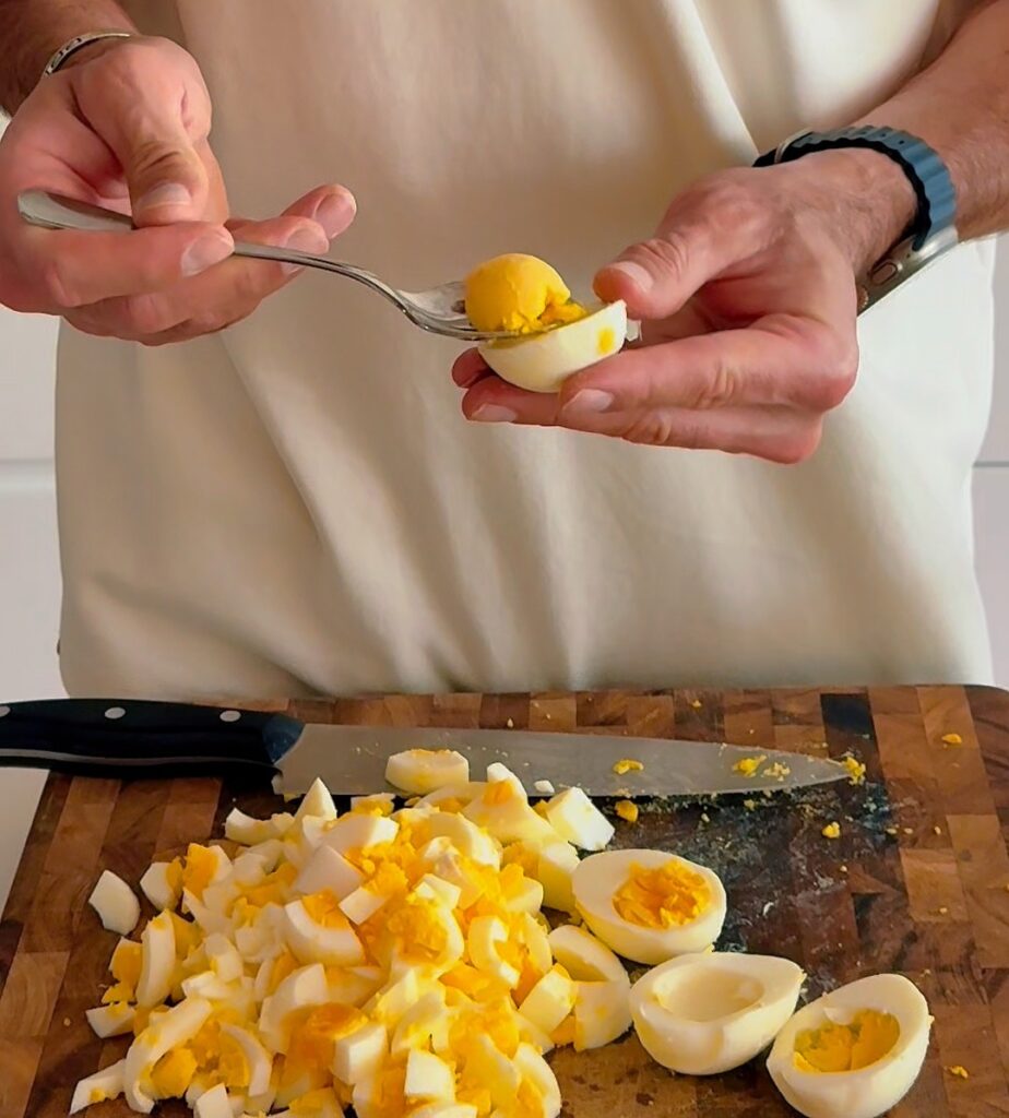 Adding egg yolks into chopped egg salad mixture