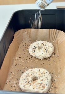 Unbaked gluten-free bagel dough shaped and resting on parchment-lined tray