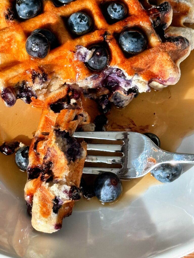 fork cutting into high protein blueberry waffle