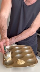 Filling a muffin tin with high protein snickerdoodle muffin batter
