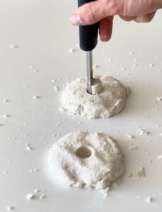 Hand shaping a hole in gluten-free bagel dough before baking
