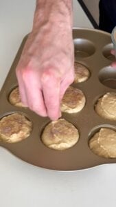 Sprinkling cinnamon sugar on snickerdoodle muffin batter before baking