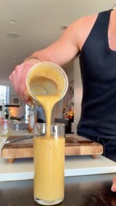 Whole orange coffee cottage cheese smoothie being poured into a glass