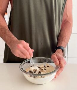 Stirring Oreo pieces into a cheesecake protein bowl