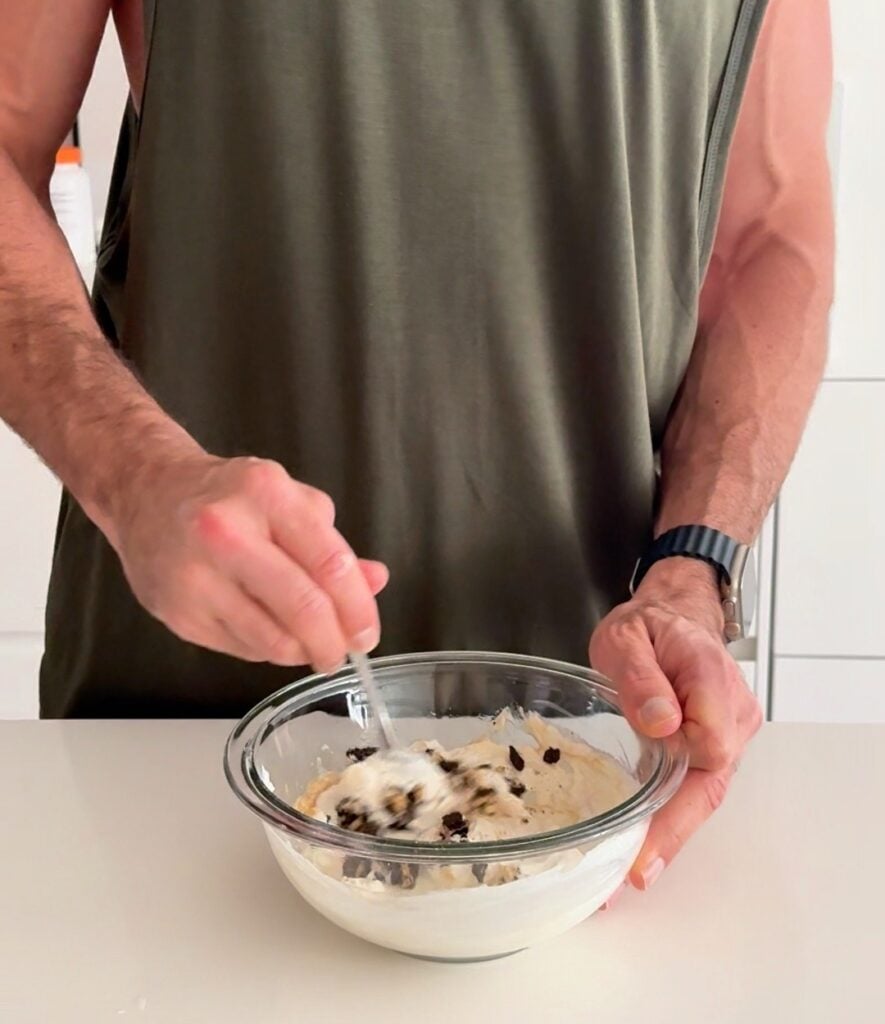 Stirring Oreo pieces into a cheesecake protein bowl