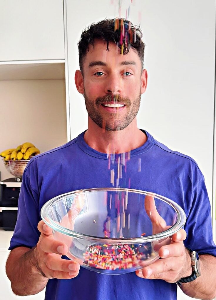 Jacob, founder of BakedLean, adding sprinkles to birthday cake protein donut holes