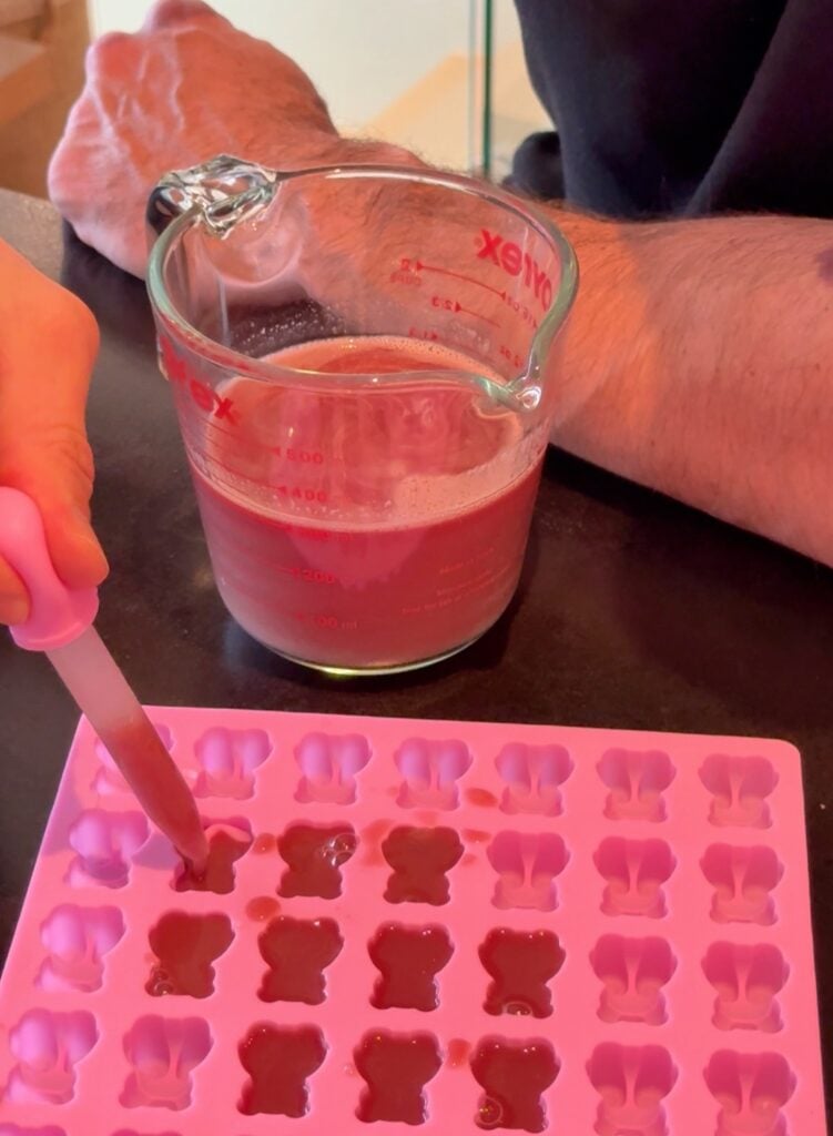 Silicone mold filled with pomegranate creatine gummy mixture