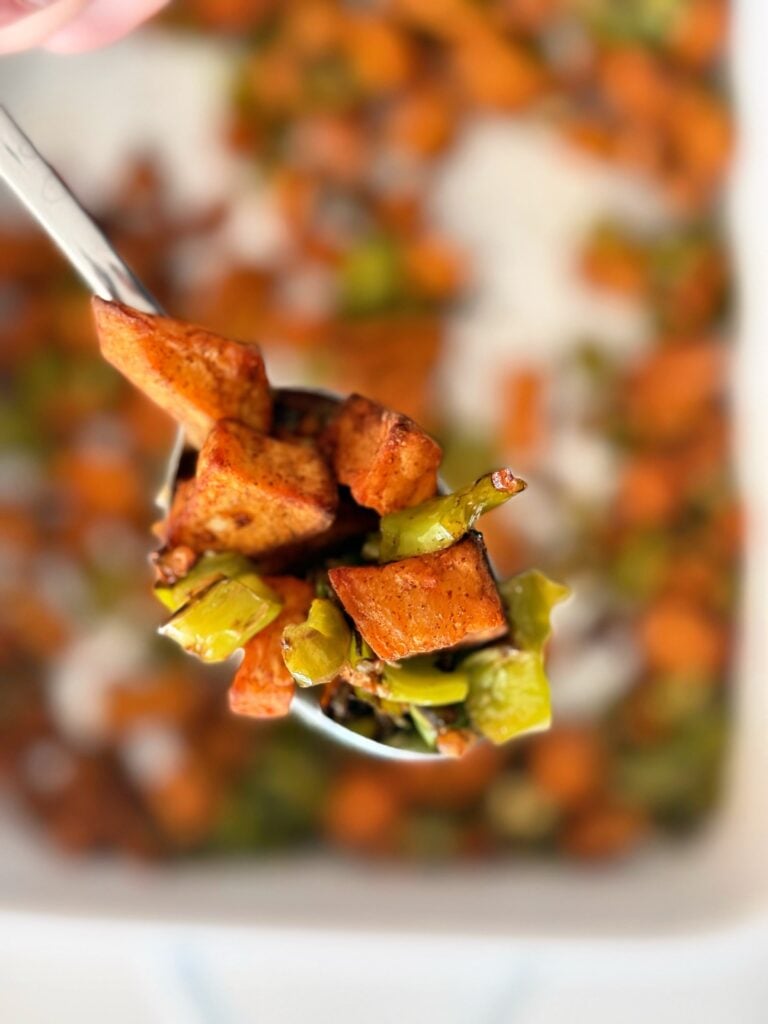 Close-up of crispy roasted sweet potato cubes and blistered shishito peppers, highlighting a high-fiber plant-based meal.