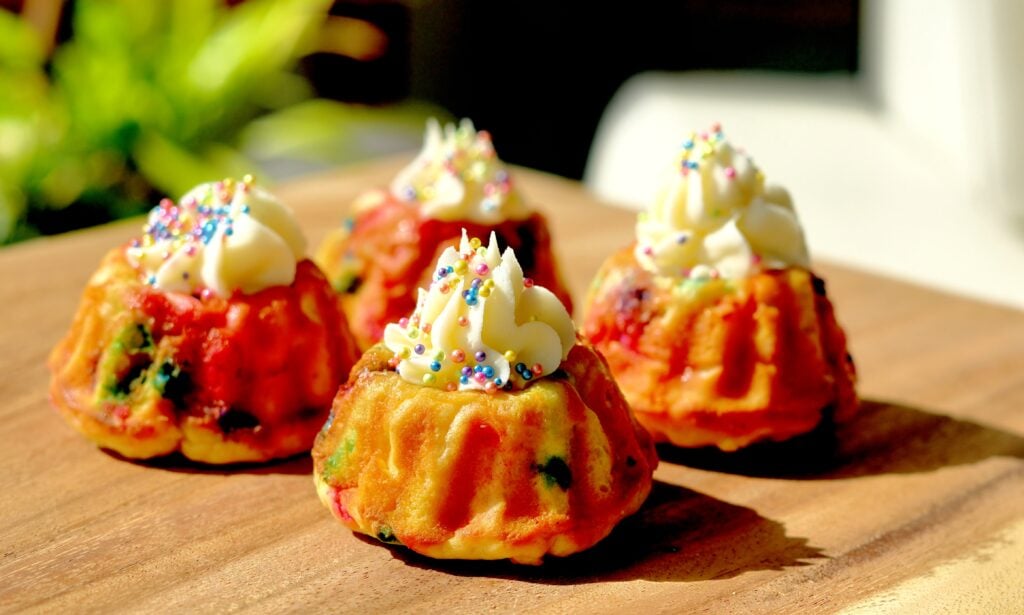 A close-up of a high-protein mini bundt cake showing the rainbow sprinkles and ridges.