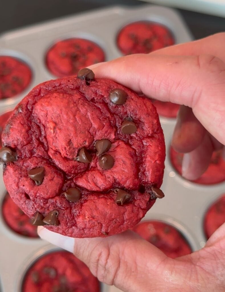 Hand holding a red velvet protein cupcake with chocolate chips