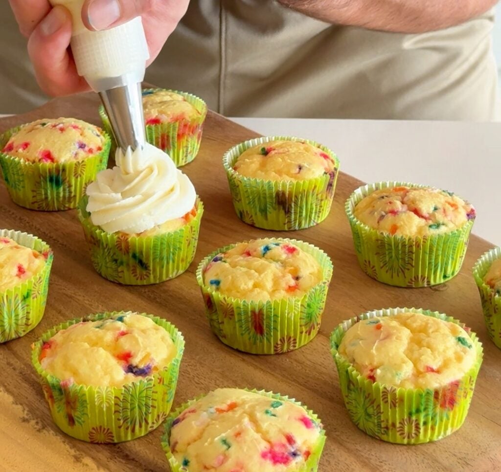 A tray of 16 funfetti protein cupcakes with rainbow sprinkles.