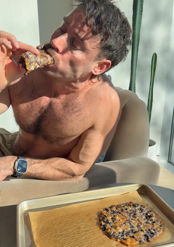 Jacob Hensley taking a bite of a high-protein bean and cheese sheet tray wrap to show its durability.