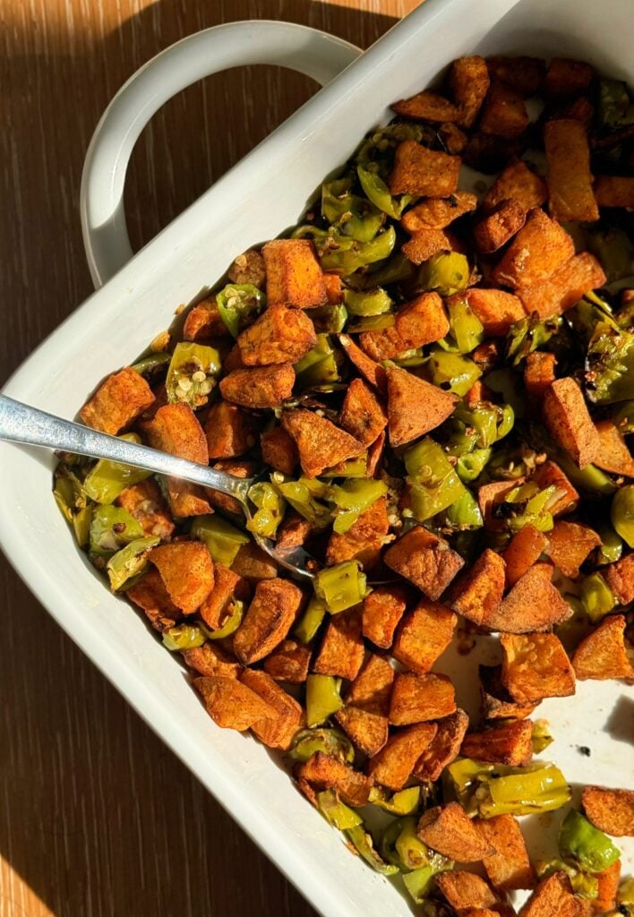 Multiple glass containers filled with sweet potato and shishito pepper hash for high-volume meal prep.