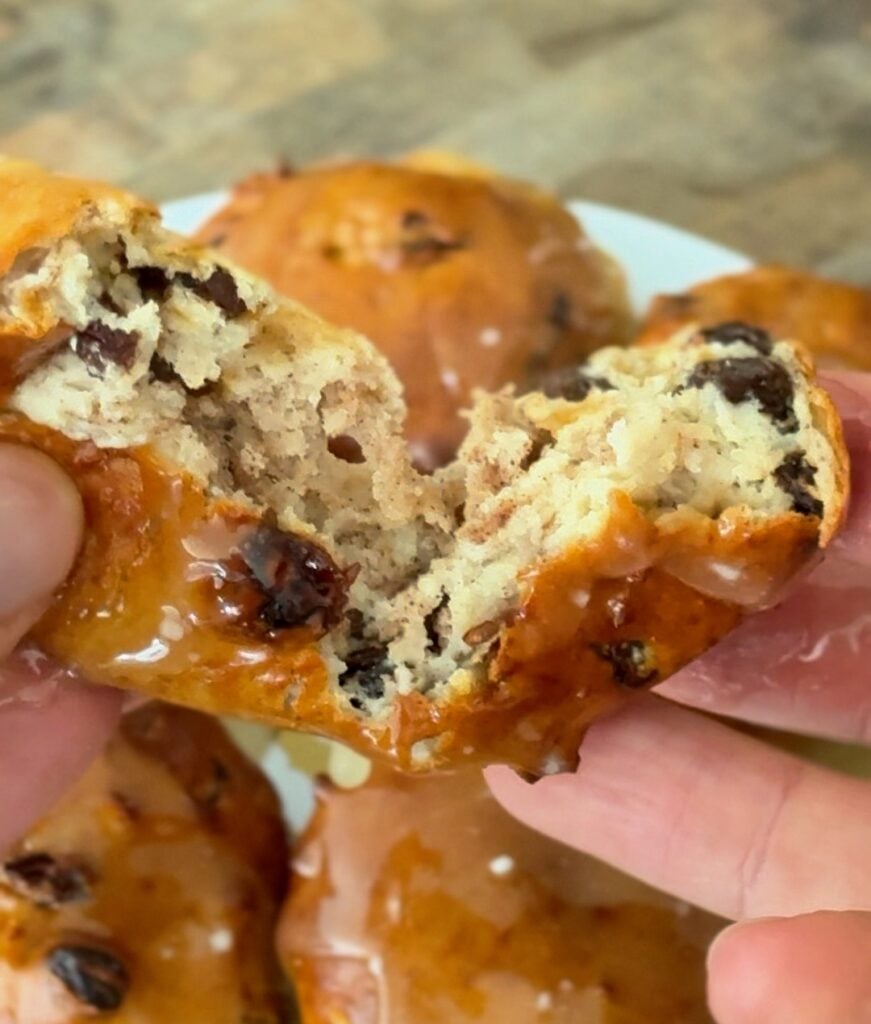 A bagel bite pulled apart to reveal a dense, chewy bready interior with visible raisins and cinnamon swirls.